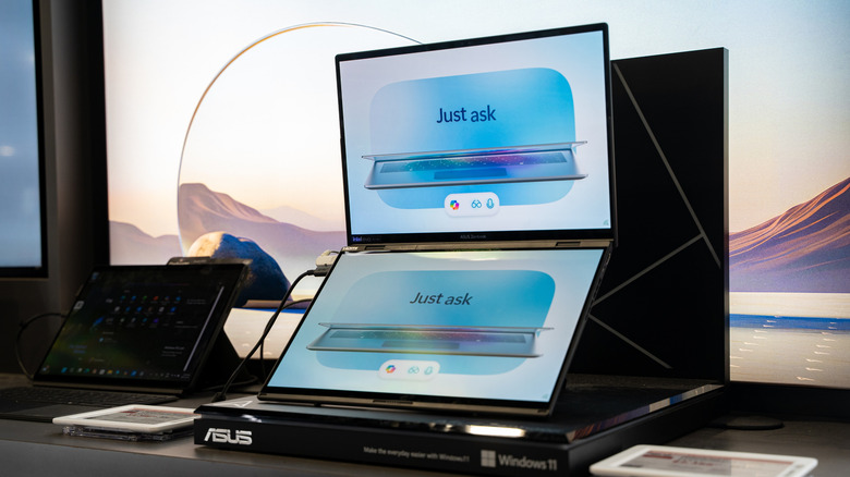 An Asus ZenBook Duo with two screens displaying 'Just Ask' graphics.