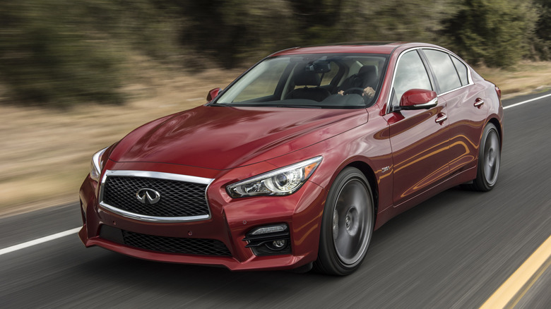 A white Infiniti Q50 Red Sport 400 cruising on an open highway.