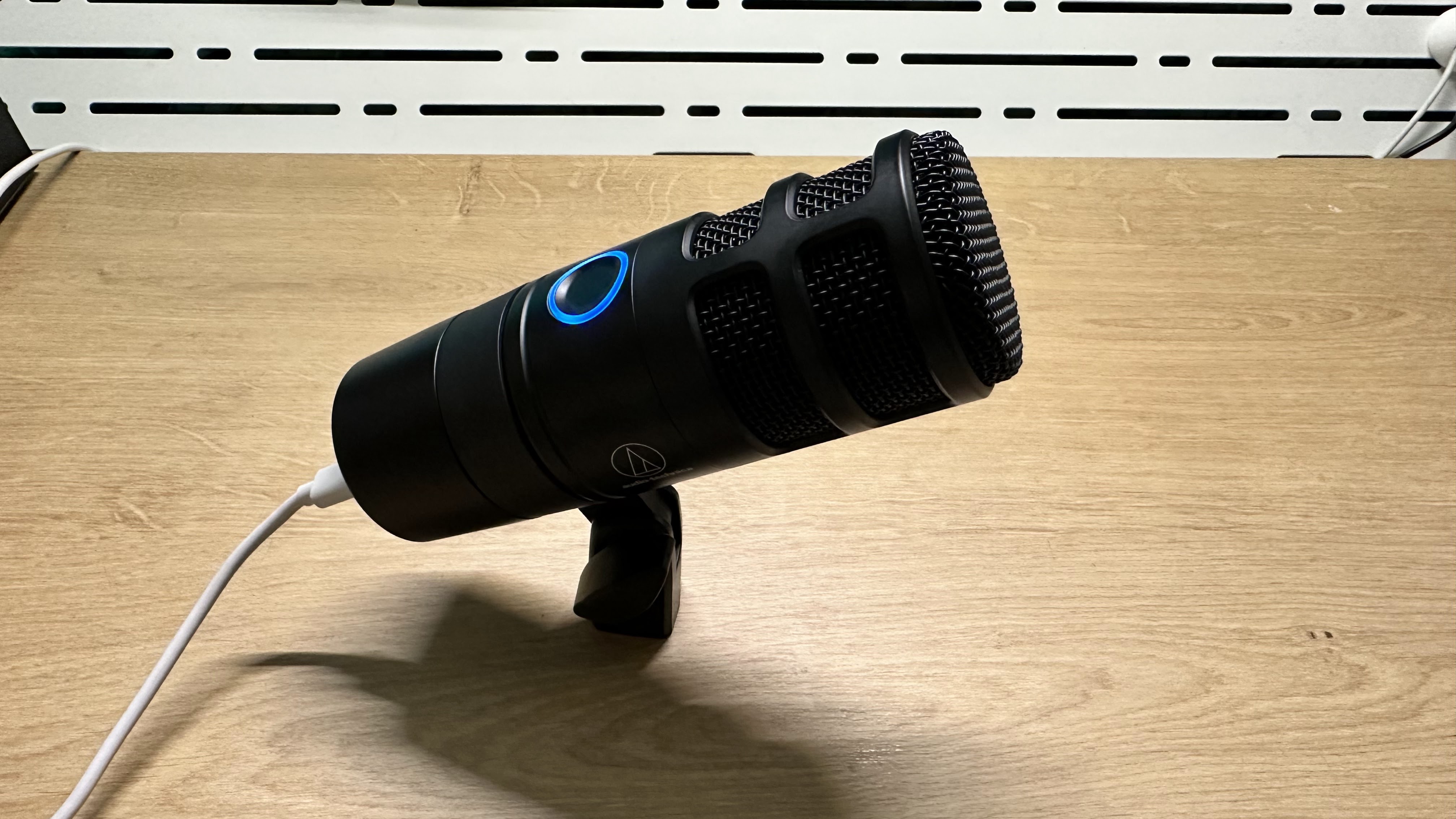 Audio-Technica AT2040USB dynamic microphone resting on a wooden desk.