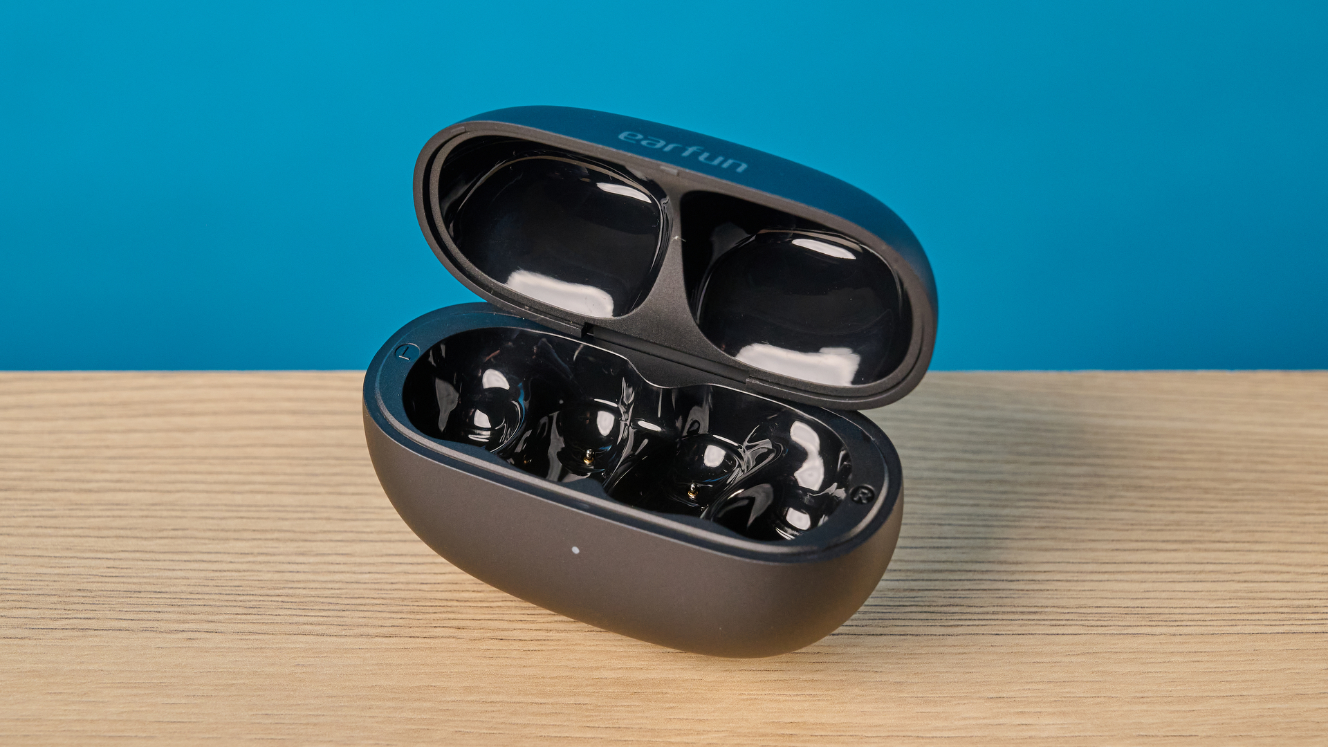 EarFun Clip 2 earbuds sitting next to their compact matte black charging case