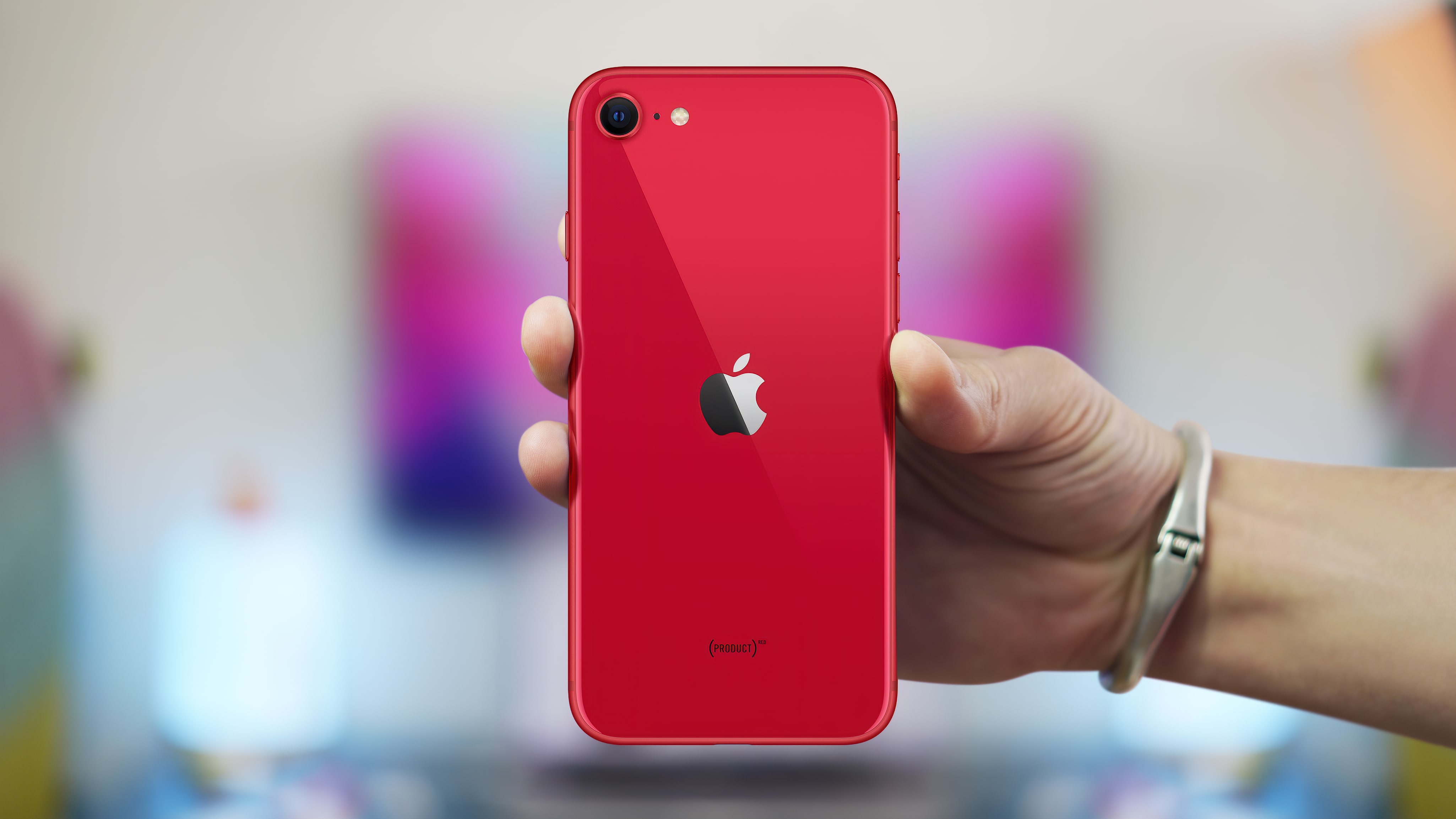 A person holding a red Apple iPhone, representing mainstream secure hardware.