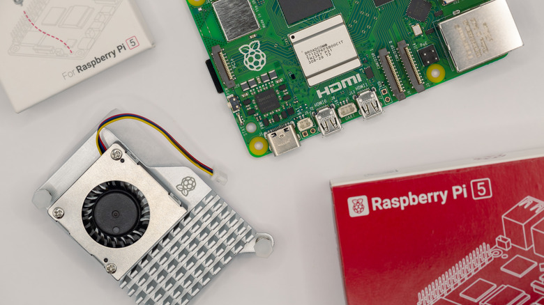 The official Raspberry Pi 5 Active Cooler shown next to the board and its retail packaging.