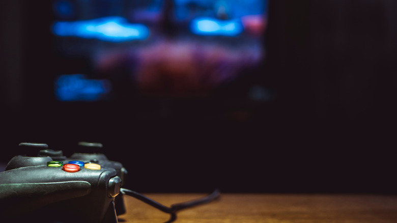 A wireless game controller sitting on a coffee table in front of a living room television.