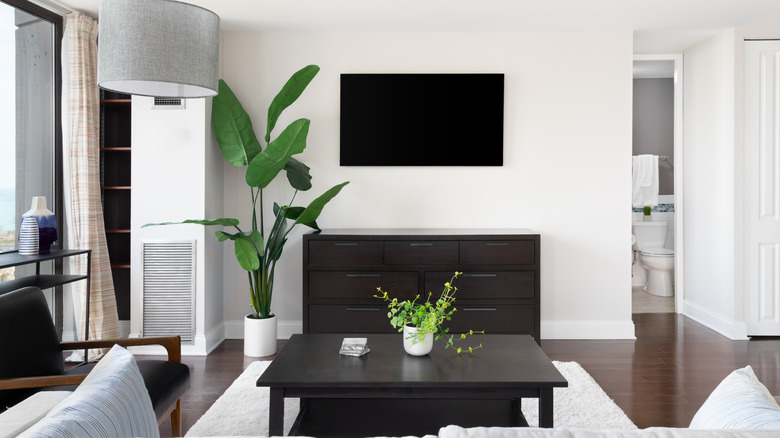 Minimalist living room with a wall-mounted flat-screen television positioned over a dark wood dresser.