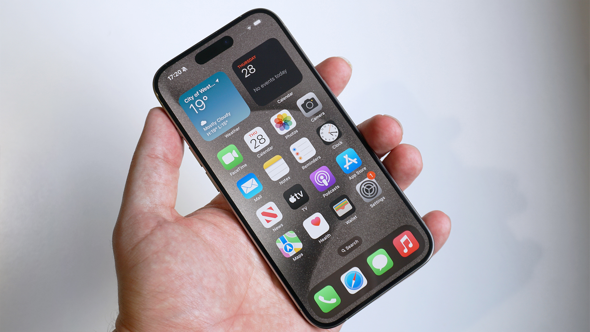 Handheld view of a titanium iPhone 15 Pro showing its triple-camera system.