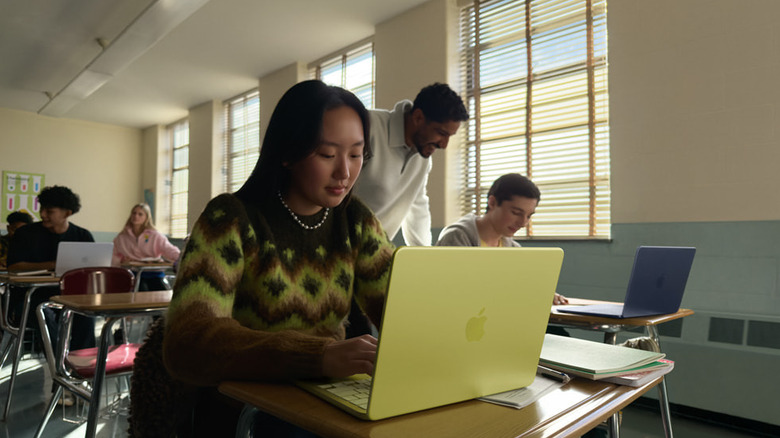 A student using a bright yellow laptop in a classroom setting.