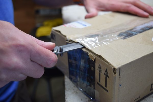 The Gerber Paraframe knife being used to slice through the tape of a cardboard box.