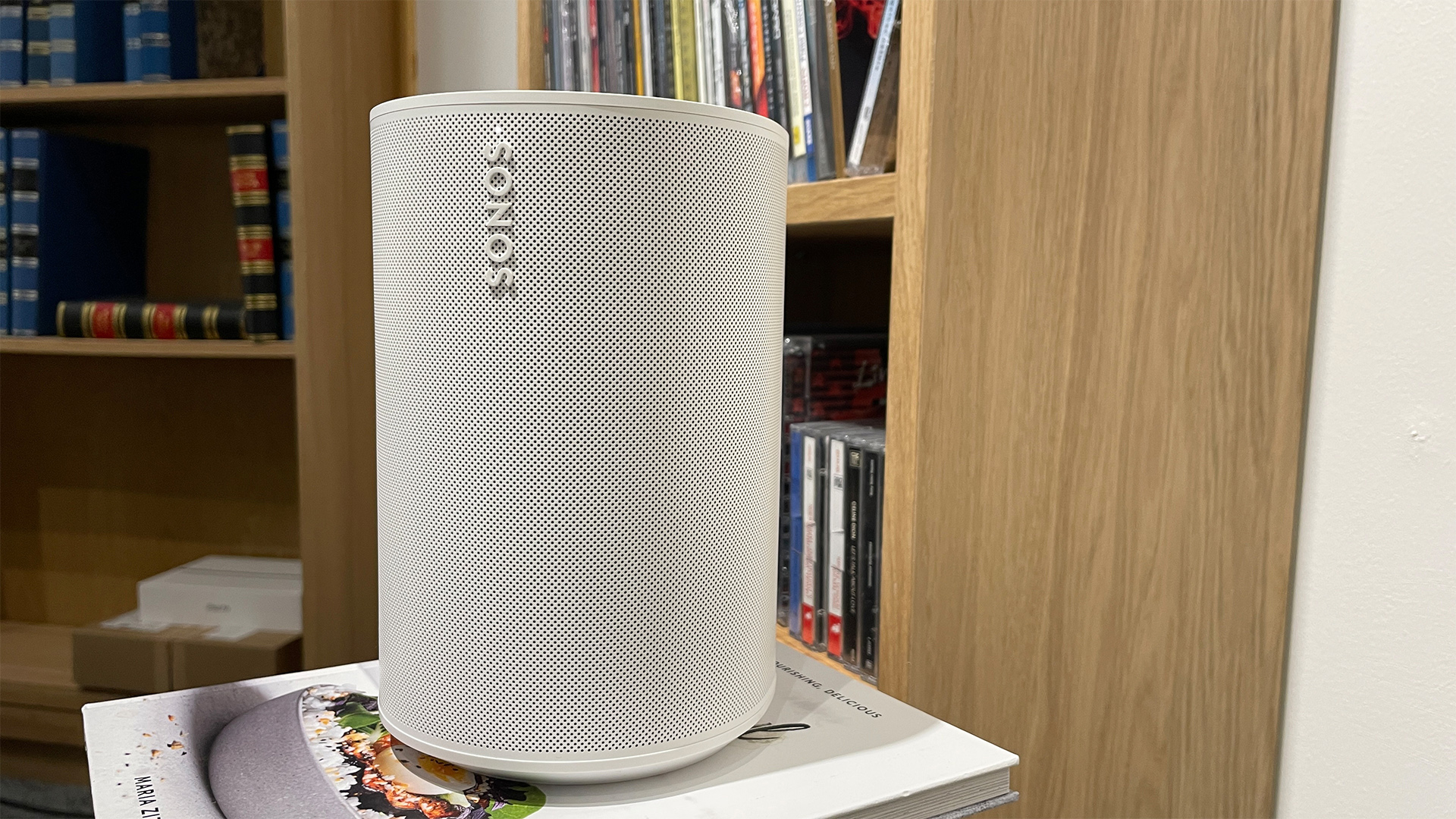A white Sonos Era 100 speaker sitting on a clean, modern white shelf.