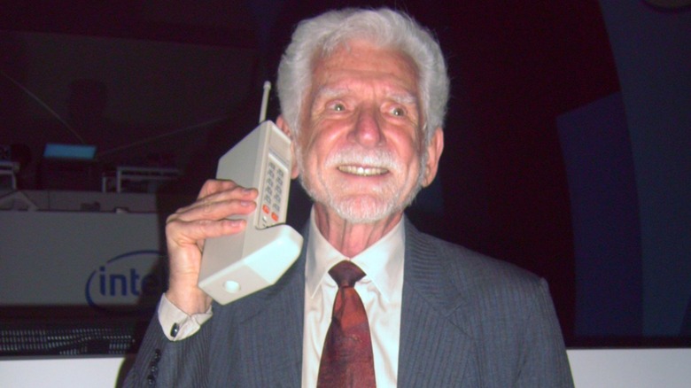 Martin Cooper holding the large Motorola DynaTAC cellular phone prototype to his ear.