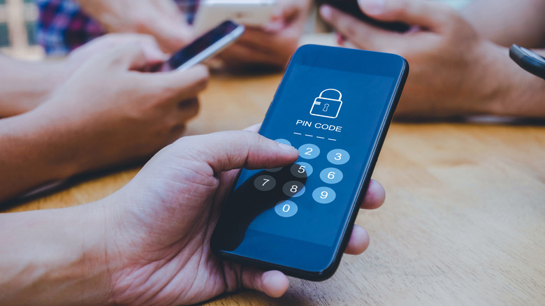 A close-up of a hand holding a smartphone that is prompting the user to enter a SIM PIN code.