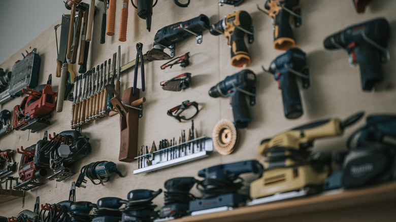 A neatly organized wall of hand tools and power tools hanging in a professional workshop.