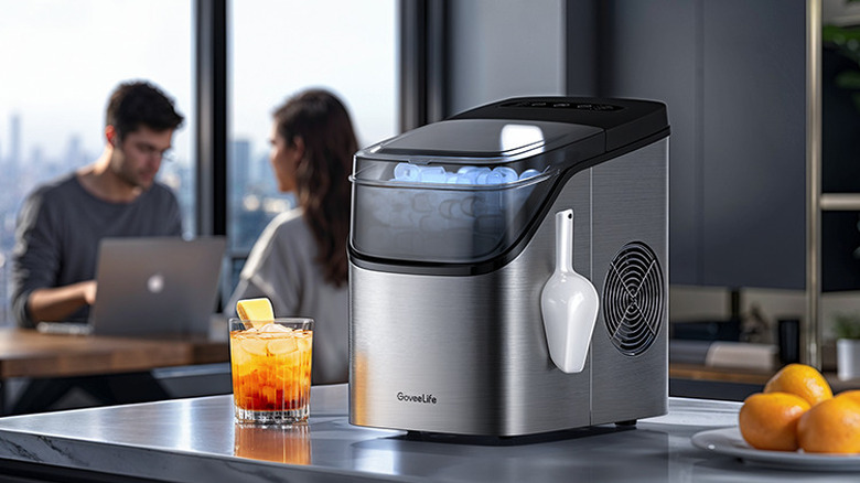 A GoveeLife smart ice maker placed on a kitchen counter with people in the background.