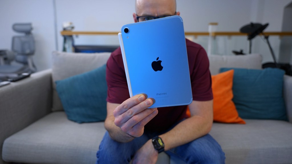 A hand holding the compact iPad Mini 7 to show its relative size.