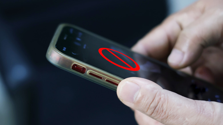A person holding a smartphone showing a red restricted sign icon on the screen.