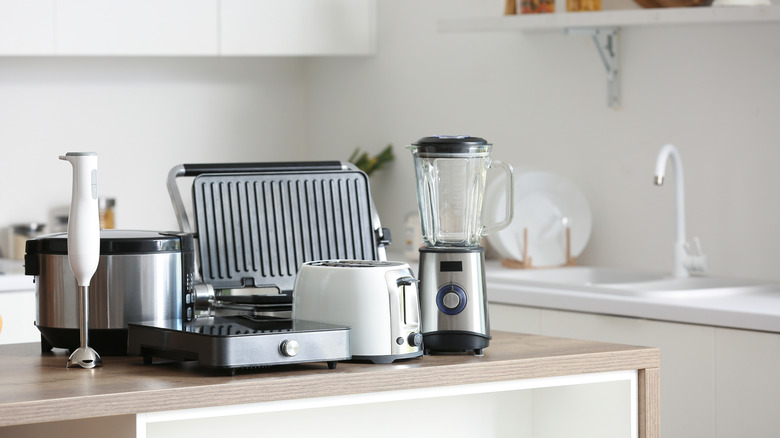 A variety of professional stainless steel and wooden kitchen utensils arranged neatly on a countertop.